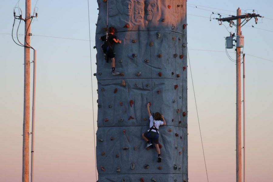 Students climb up rock wall.