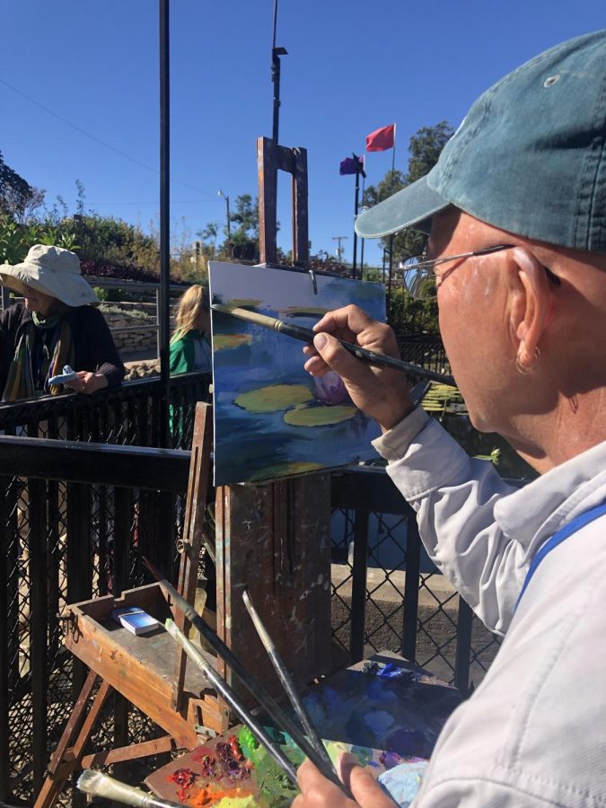 Artist concentrates on painting lily pads. 