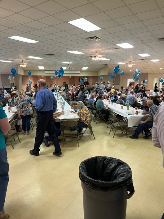 Community gathers in St. Ambrose fellowship hall to eat lunch plates. 