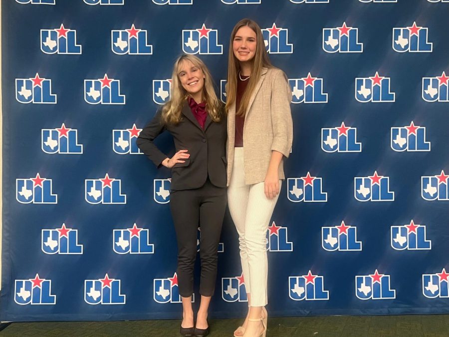 Sophomore Lily Terrell and junior Chloe Jones in front of UIL Congress state banner. 