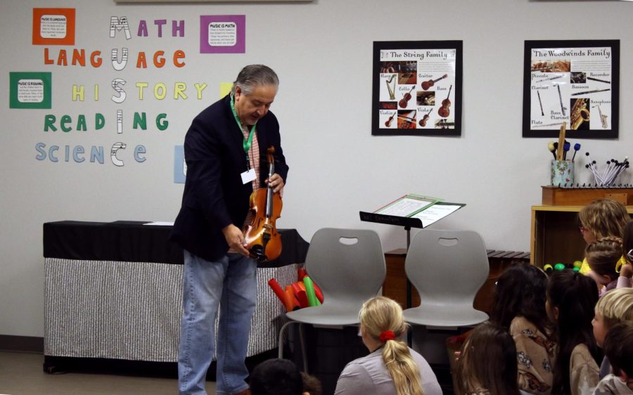 Maestro Guzman shows fourth graders a violin. 