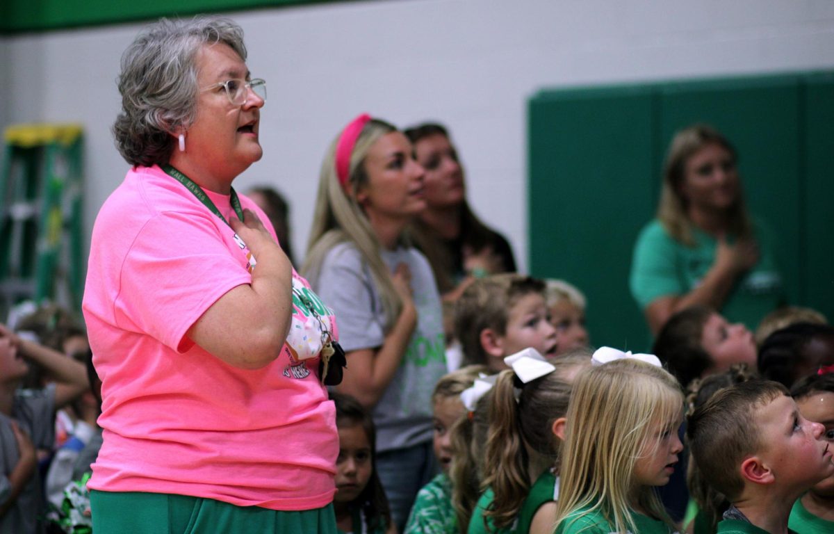 Elementary music teacher Deja Armstrong sings at a pep rally, surrounded by her students.