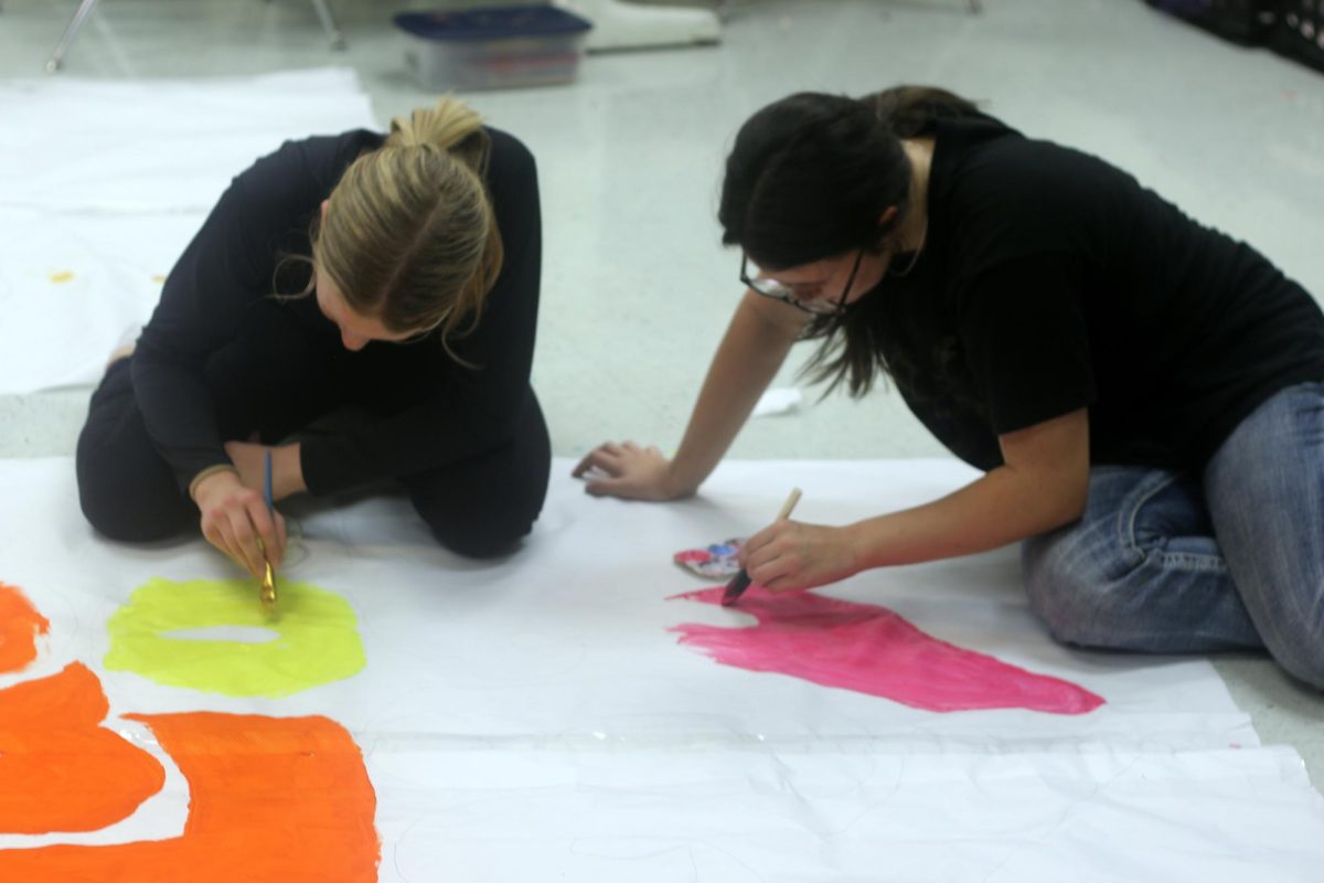 Eighth-grade advanced art students Morgan Rutledge and Addison Sowell work on a pep rally sign during class.